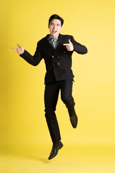 Portrait of Asian male businessman. wearing a suit and posing on a yellow background photo