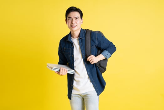 Portrait of Asian male student posing on yellow background photo