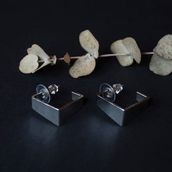 Silver earrings on a black background with decor photo