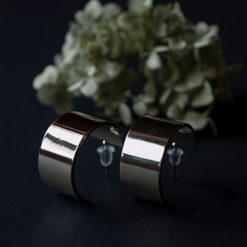 Silver earrings on a black background with decor photo