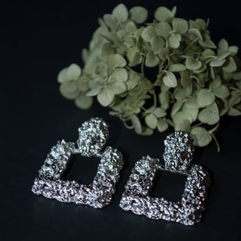 Silver earrings on a black background with decor photo