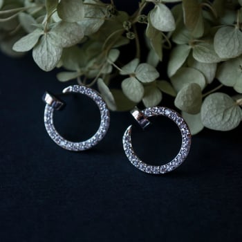 Silver earrings on a black background with decor photo