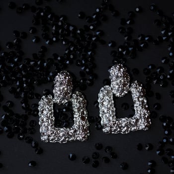 Silver earrings on a black background with decor photo