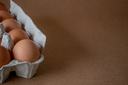 Fresh chicken eggs in a paper tray on the table, selective focus photo