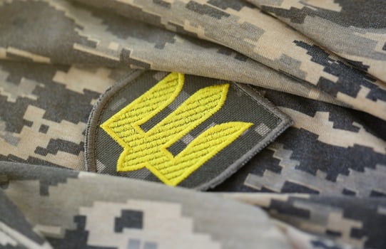 Symbol of Ukrainian army on the camouflage uniform of a Ukrainian soldier. The concept of war in Ukraine, patriotism and protecting your country from occupiers photo