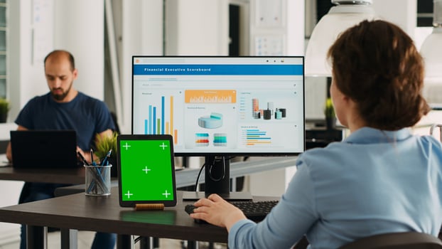 Business person using pc at workstation, having greenscreen display template on tablet in front of her. Manager planning startup operations and checking isolated mockup layout on device. photo