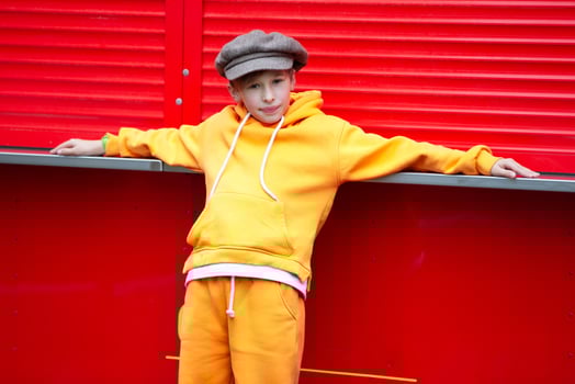 Happy boy in a vintage hat and orange suit posing at a red kiosk. photo