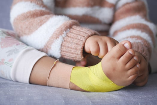 Elastic therapeutic yellow tape applied to child leg. Kinesio Taping therapy for injury photo