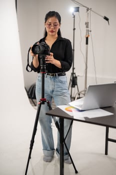 A professional Asian female photographer is adjusting her DSLR camera on a tripod stand. photo