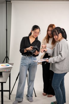 A female photographer is talking and showing images on the camera to her team, working in the studio photo