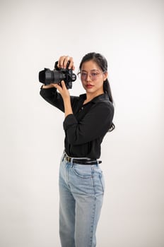 A professional, confident Asian female photographer is taking pictures in a photoshoot studio. photo