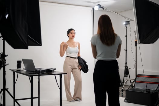A professional photographer is taking pictures of an attractive young Asian female model in a studio photo