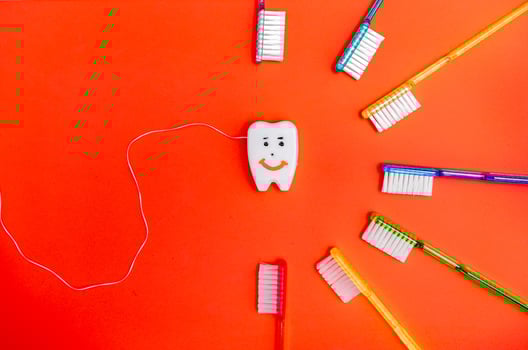 Colorful tooth brushes arounf toy smiling tooth. Dental concept. photo