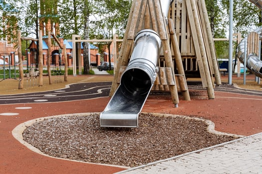 Modern children's playground for outdoor games, a slide pipe made of metal, pyramids made of wood, rubber coating on the playground. photo