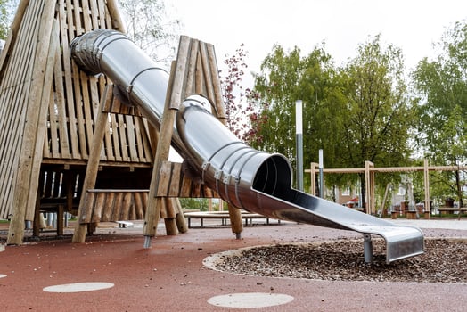 A metal slide on the playground, a modern playground for kids, a sports complex on the street, a wooden climber, an area for walking with children. photo