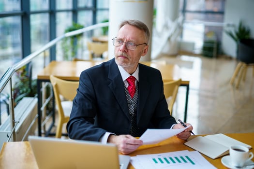 Content senior business man sitting in a dark suit. Documents in hands. Red tie. Confident. Business style concept photo