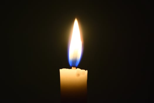 Single Candle with flame in the dark place, isolated black background photo
