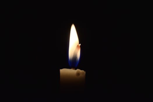 Single Candle with flame in the dark place, isolated black background photo