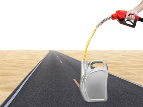 Hold the gasoline injector into the gallon. There are road and desert backgrounds. photo