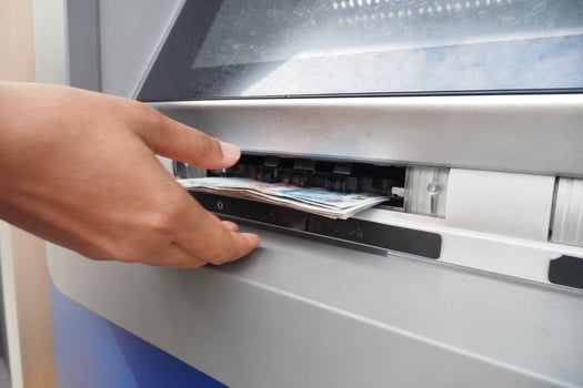 A person is withdrawing cash from an ATM machine using their thumb gesture photo