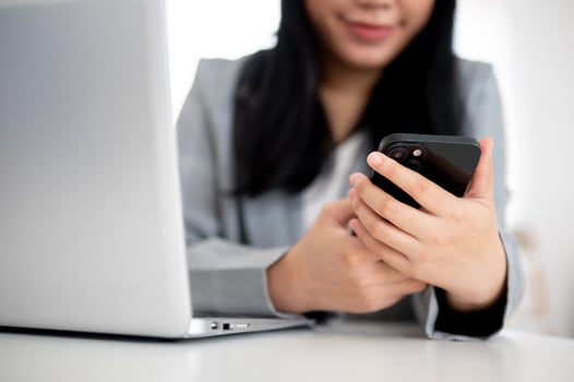 A cropped shot of an Asian businesswoman is using her smartphone at her desk in the office. photo
