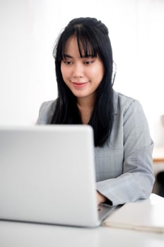 A beautiful Asian businesswoman or female secretary is working on her laptop in a modern office. photo