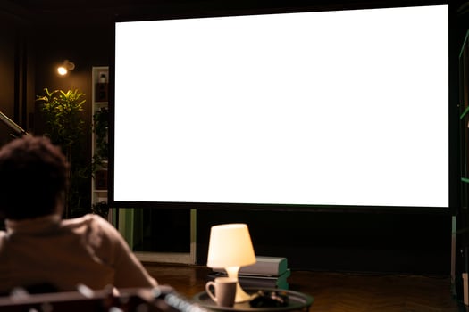 Man watching football competition live on ultrawide isolated screen smart TV, cheering for favorite team. Sports fan on couch in front of mockup television set display looking at soccer photo