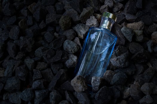 Perfume Blue transparent bottle in gravel or coral background photo