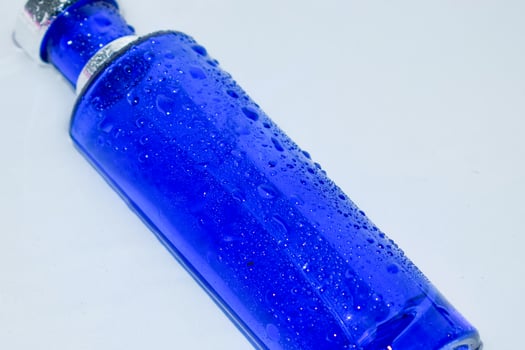 Perfume Dark Blue transparent bottle in water background photo
