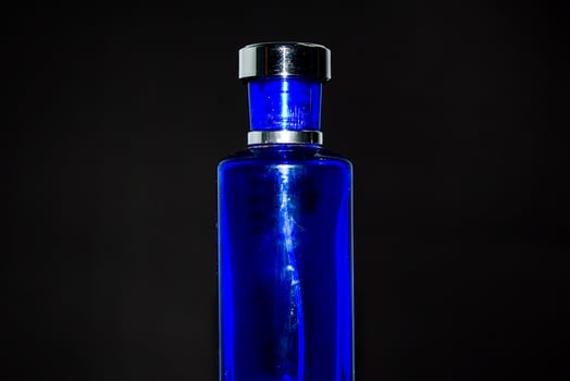 Transparent Dark Blue Bottle Perfume isolated black background for mock up design photo