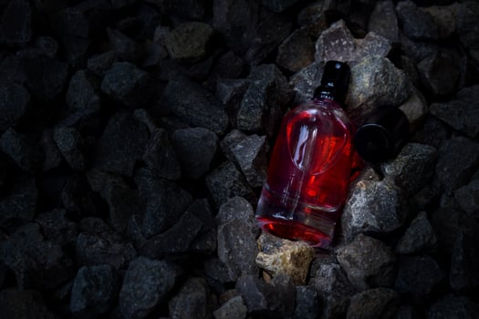 Perfume Red transparent bottle in gravel or coral background photo