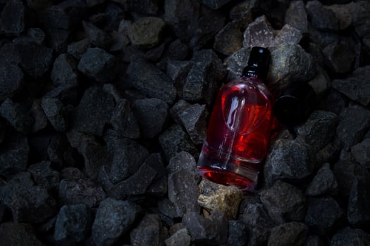 Perfume Red transparent bottle in gravel or coral background photo