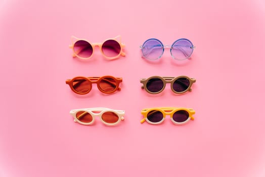 Different stylish sunglasses on pink background photo