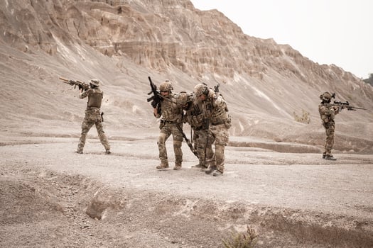 Soldiers in camouflage uniforms aiming with their riflesready to fire during military operation in the desert soldiers training  in a military operation photo