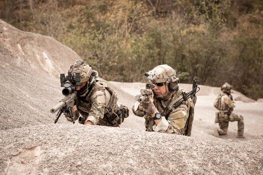 Soldiers in camouflage uniforms aiming with their riflesready to fire during military operation in the desert soldiers training  in a military operation photo