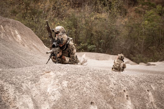 Soldiers in camouflage uniforms aiming with their riflesready to fire during military operation in the desert soldiers training  in a military operation photo