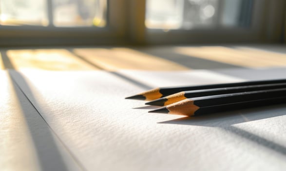 Graphite pencils and white paper illuminated by natural through a window photo