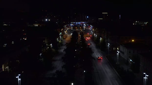 Top view of dark city at night with glowing lanterns. Stock footage. Beautiful view of highway with cars and lanterns. Night road in the center of modern city with lanterns photo