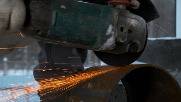 Man cutting metal piece of pipe with circular saw. Clip. Sparks fly from hot metal, man hard working over the steel. photo