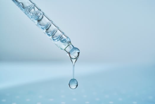 Pipette with serum on a blue background. photo