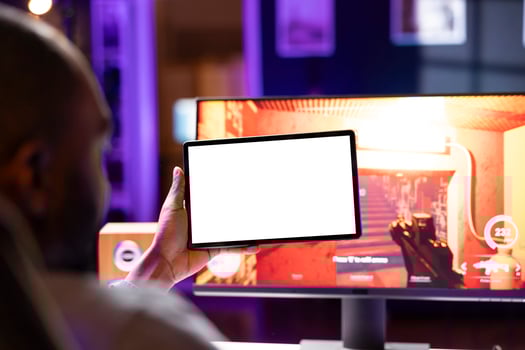Player looking at isolated screen tablet, taking break from playing singleplayer videogame on gaming computer, close up. Man in home using mockup portable device while enjoying game photo