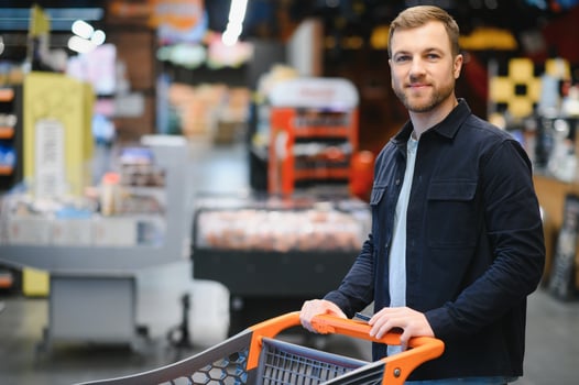Handsome man buying some healthy food and drink in modern supermarket or grocery store. Lifestyle and consumerism concept. photo