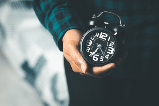 Time management concept. Man hands holding Black retro alarm clock. Time to wake up for the morning routine photo