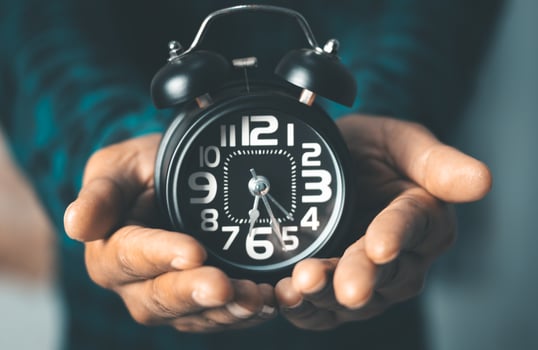Time management concept. Man hands holding Black retro alarm clock. Time to wake up for the morning routine photo