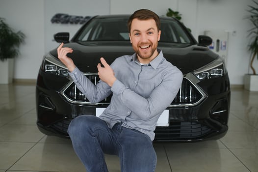 Visiting car dealership. Handsome bearded man is stroking his new car and smiling. photo