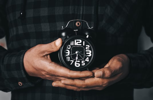 Time management concept. Man hands holding Black retro alarm clock. Time to wake up for the morning routine photo