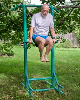 senior male exercising on outdoor fitness tower photo