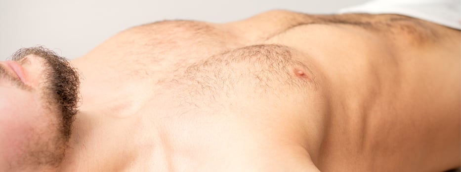 Hairy body, stomach, and chest of a man lying before epilation. photo