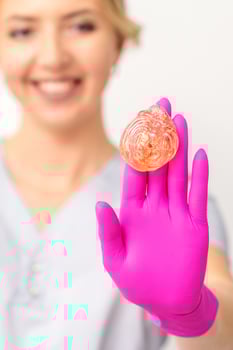 Yellow sugar paste in hand master of depilation. Smiling beautician holding wax for depilation over white background. Concept epilation. photo