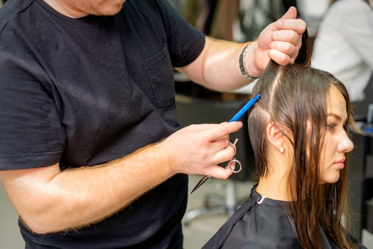 Hairdresser divides female hair into sections with comb holding hair with her hands in hair salon close up. photo